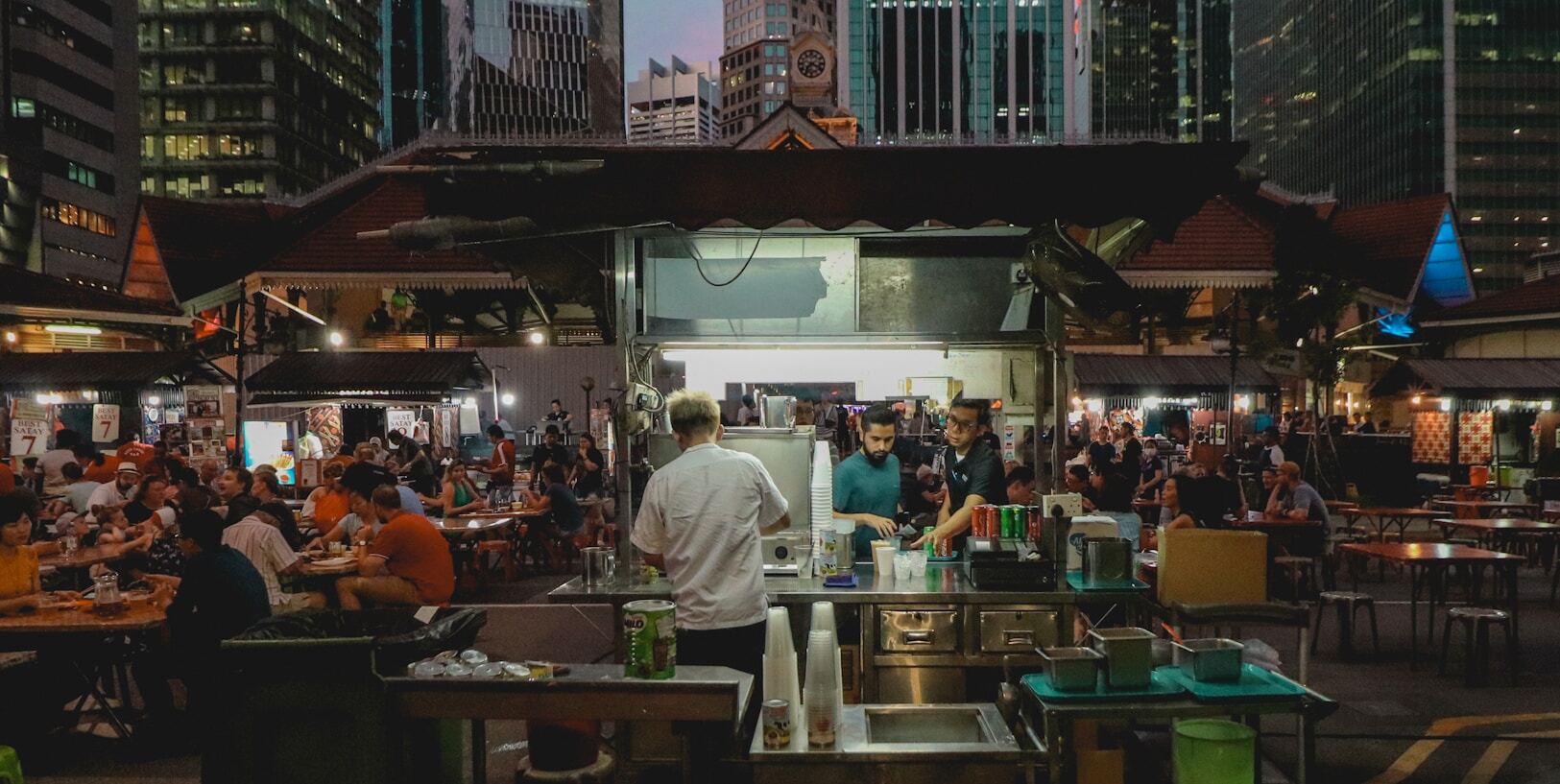 Nighttime scene of a street food vendor in a city, highlighting the vibrant culture of iconic hawker centers.