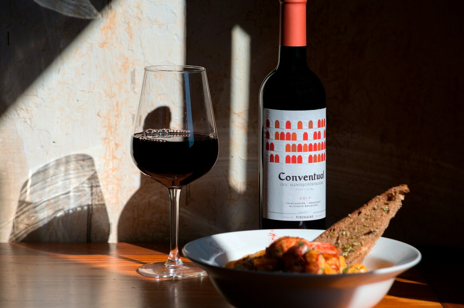 A bottle of bold red wine beside a bowl of rich, savory food, showcasing a perfect complementary pairing.