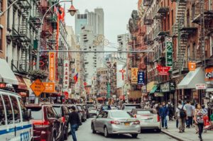 A bustling Chinatown street filled with pedestrians and cars, highlighting hidden culinary gems in the area.