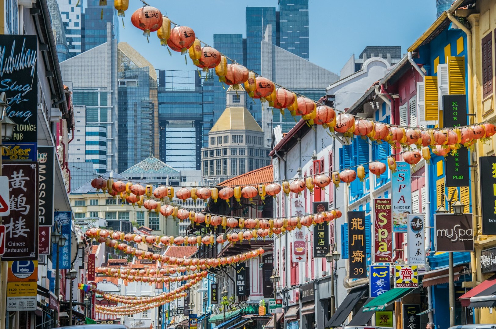 A lively street scene in Chinatown, Singapore, featuring various buildings and cars, highlighting the charm of Hong Lim Market.