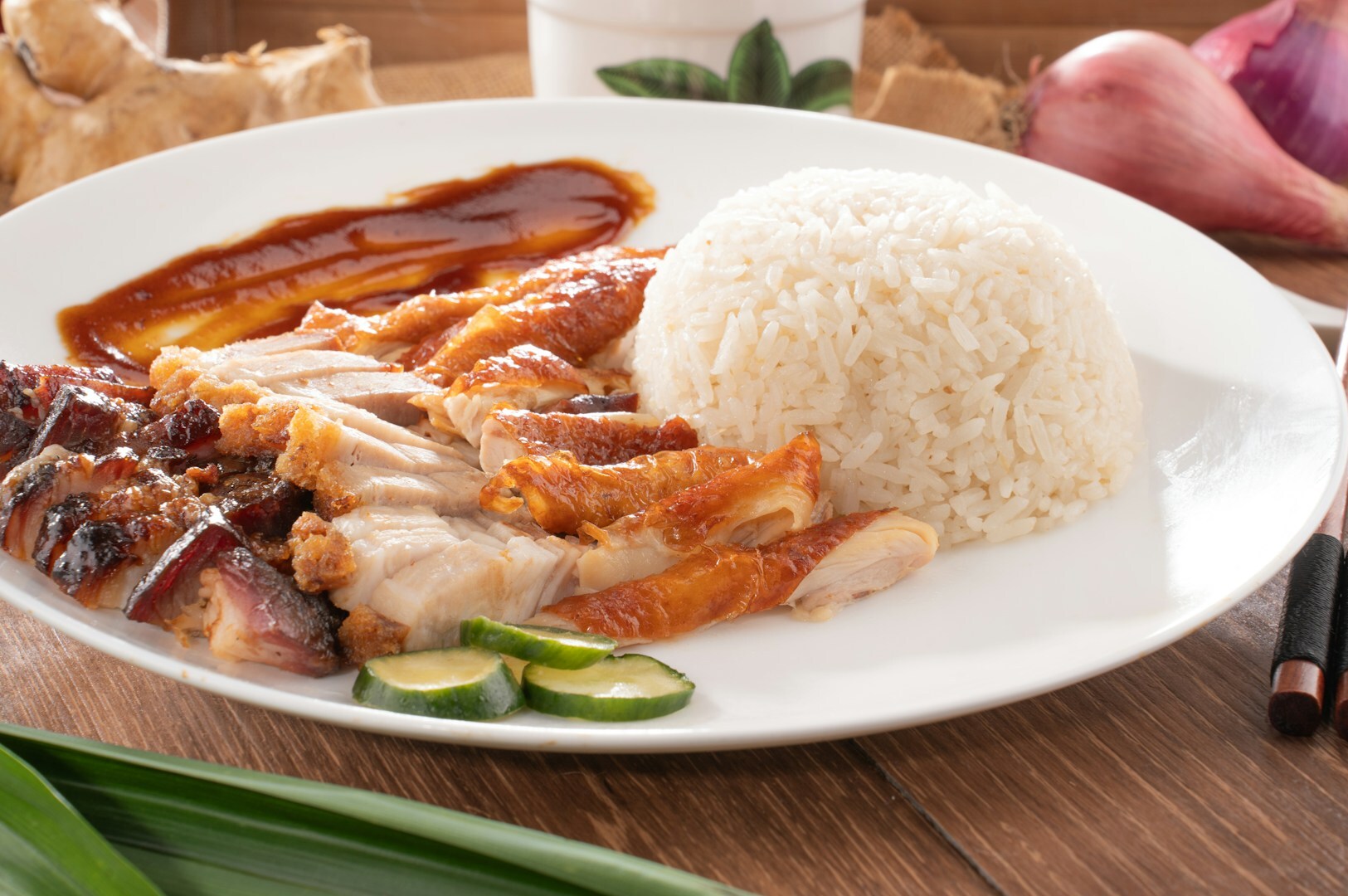 A plate featuring Hainanese chicken rice and soy sauce chicken rice, served at Maxwell Food Centre.