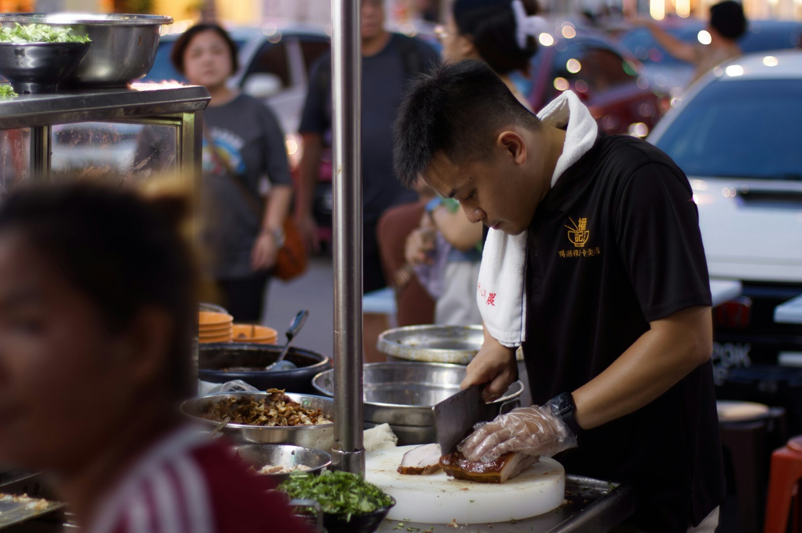 A man prepares food at a street stand, surrounded by heritage streets at sunrise and vibrant night lights.