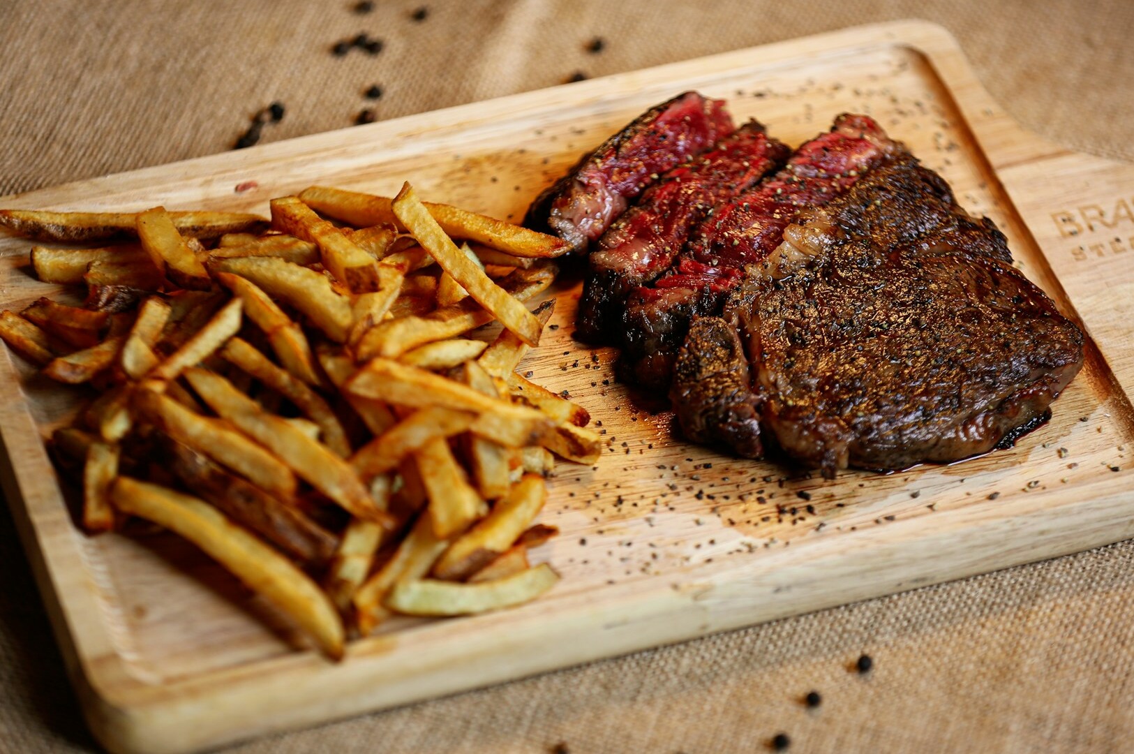 A perfectly cooked steak alongside crispy French fries on a cutting board, representing a culinary delight from Joo Chiat.