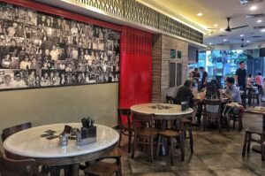 A coffee shop in Lavender MRT, Singapore, featuring tables, chairs, and a wall adorned with various photos.