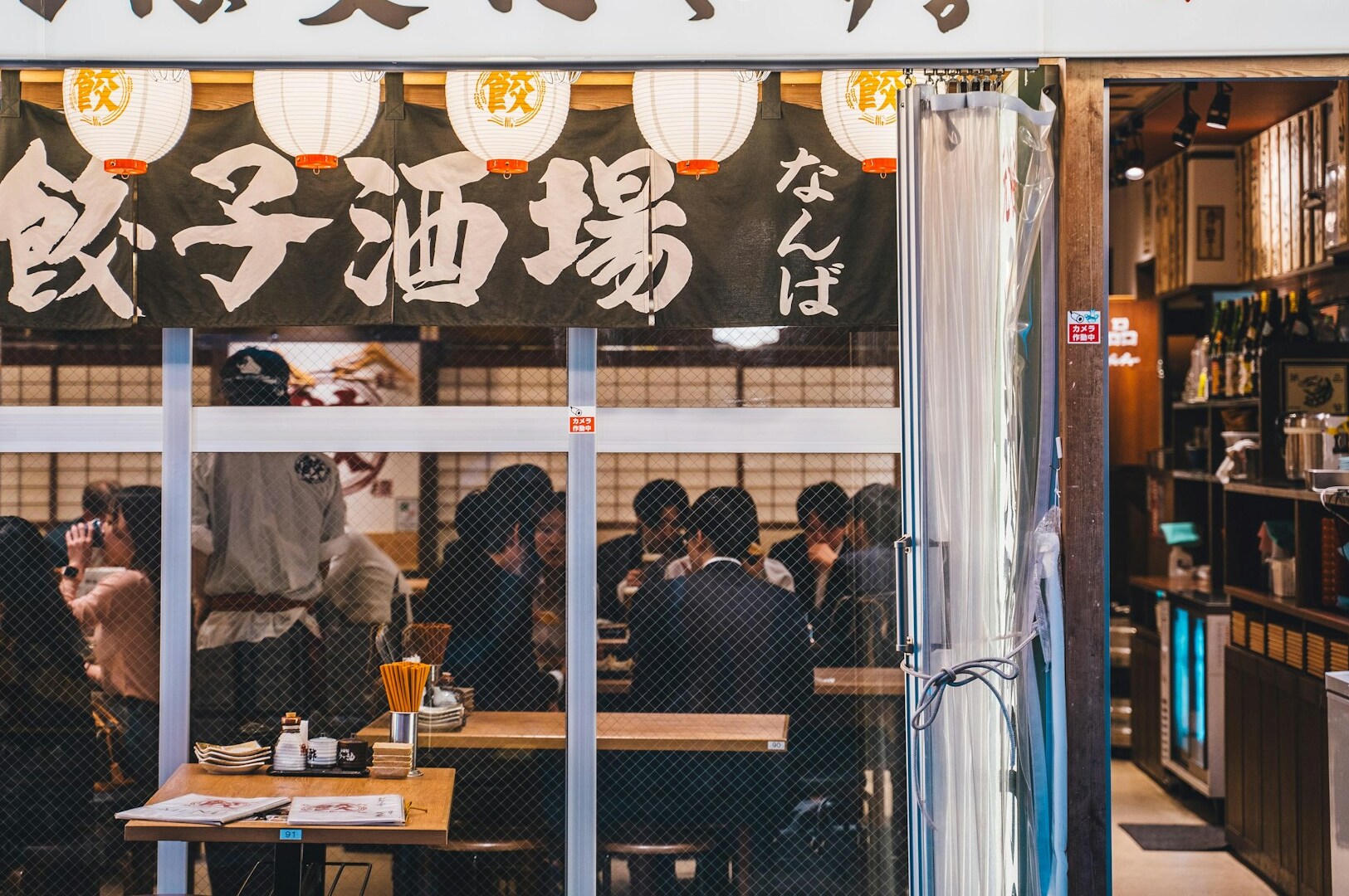 Interior of a Japanese Izakaya, featuring patrons seated at tables, enjoying food and drinks in a lively atmosphere.