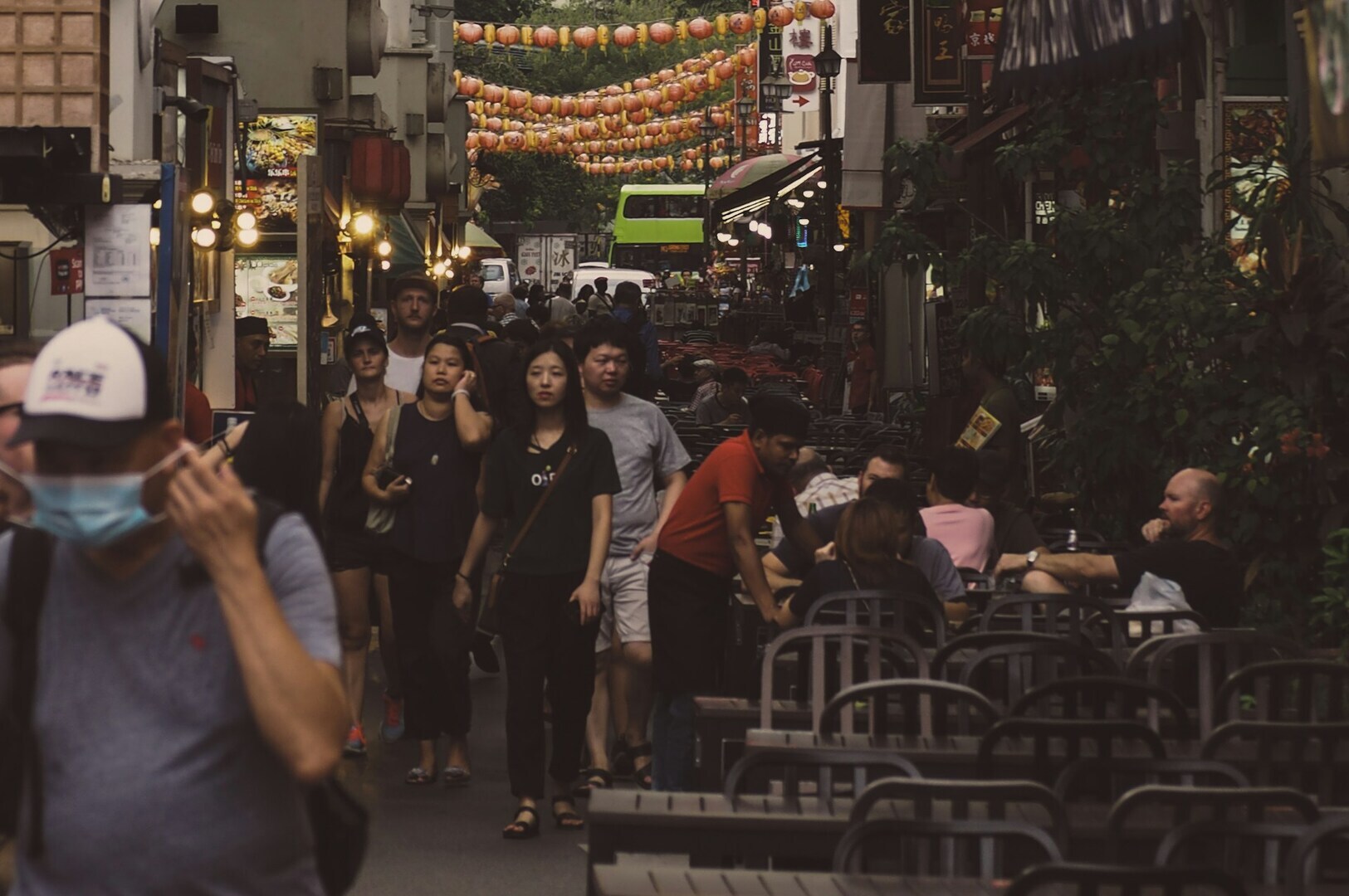 People stroll down a vibrant street lined with tables and chairs, showcasing the lively Singapore food scene.
