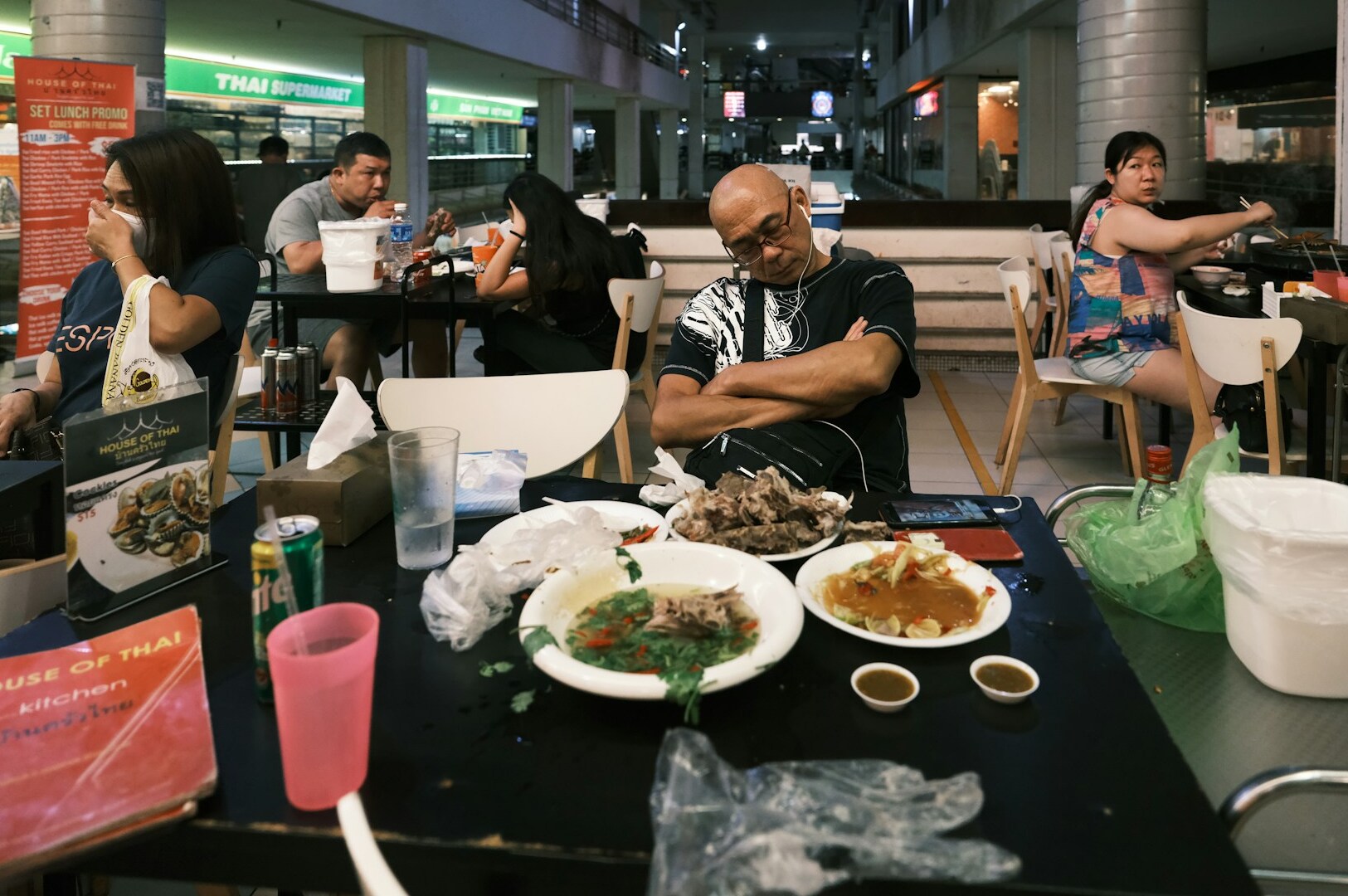 A man at a table surrounded by an assortment of dishes typical of Singapore's hawker culture.