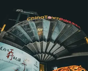 Brightly illuminated Chinatown signage mounted on a traditional-style building at night, glowing against the dark sky and city lights.