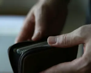 A close-up of a hand opening a wallet filled with cash and cards, symbolising personal finances, spending habits, and everyday money management.