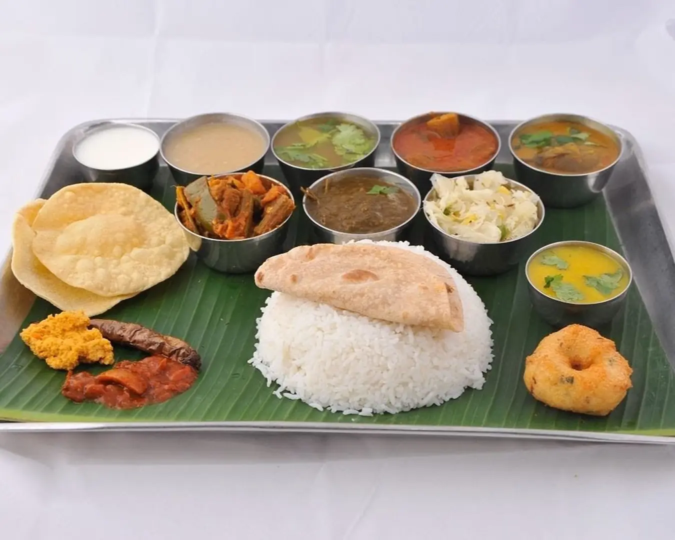 A hearty plate of fluffy white rice served alongside crispy papadom and a selection of rich, flavourful curry, creating a balanced and comforting South Asian meal.