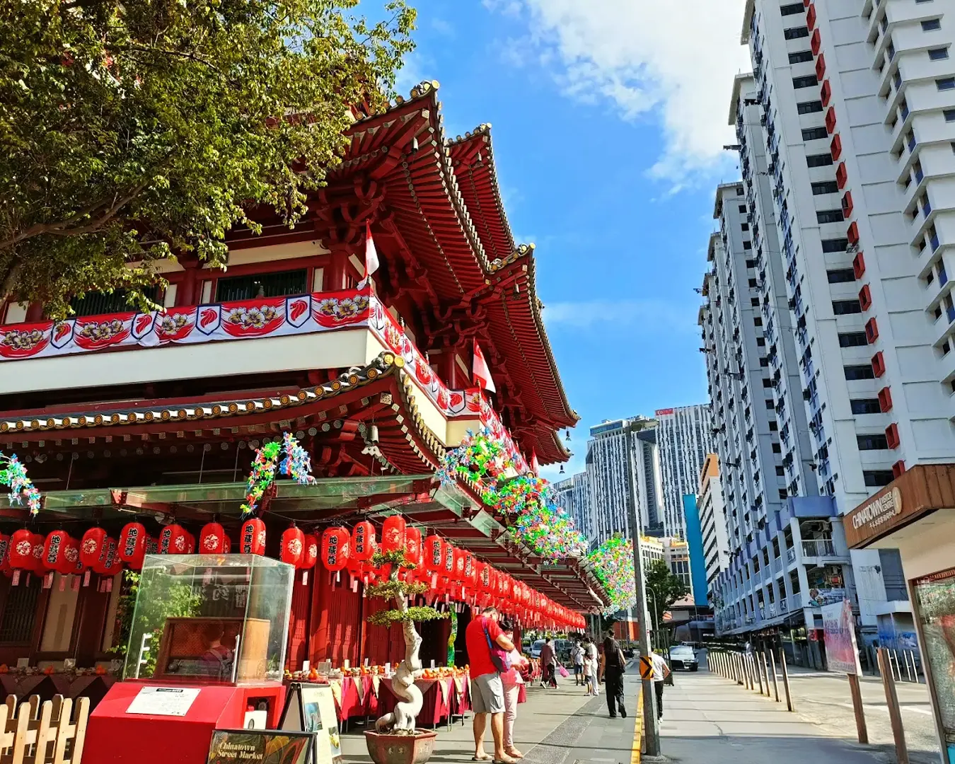 The exterior of the Buddha Tooth Relic Temple in Singapore, showcasing traditional Chinese architecture with red pillars, ornate carvings, and golden roof details.