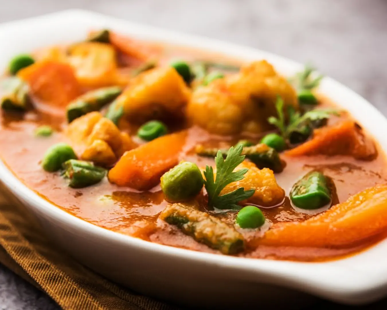 A bowl of rich and aromatic vegetable curry, with chunks of seasonal vegetables in a creamy, spiced sauce, served hot and steaming.