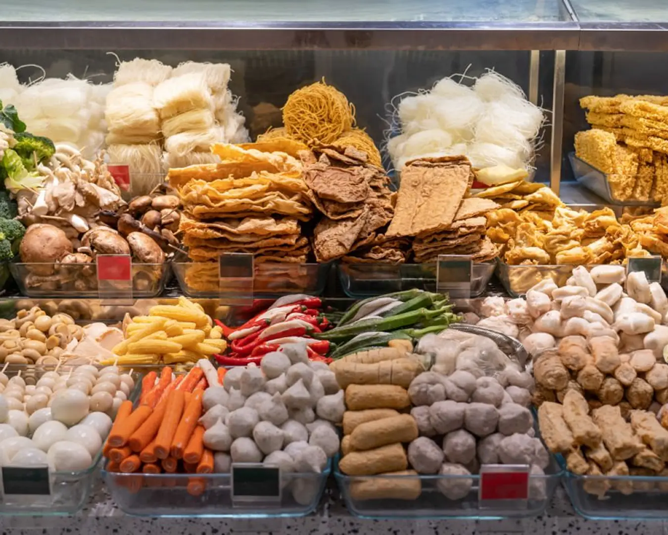 A selection of fried tofu and fish balls served with a bowl of dry noodles, arranged on a table as part of a hearty hawker meal.