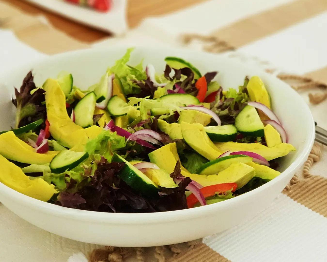 A healthy bowl of avocado slices paired with fresh vegetables like cherry tomatoes, cucumber, and lettuce, perfect for a light, nutrient-rich meal.