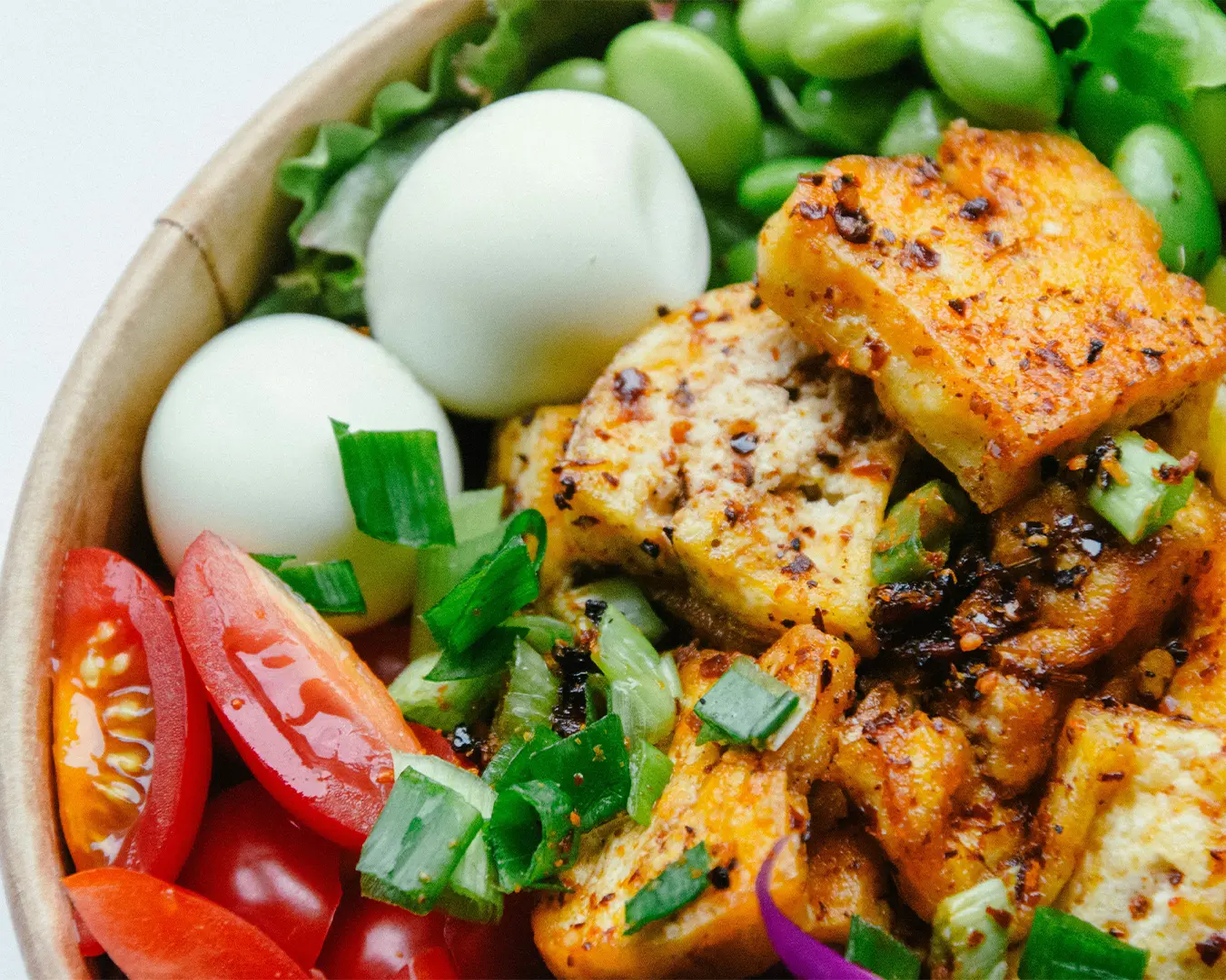 A wholesome bowl containing boiled eggs, soft tofu cubes, and crisp green beans, served as a protein-rich vegetarian option.
