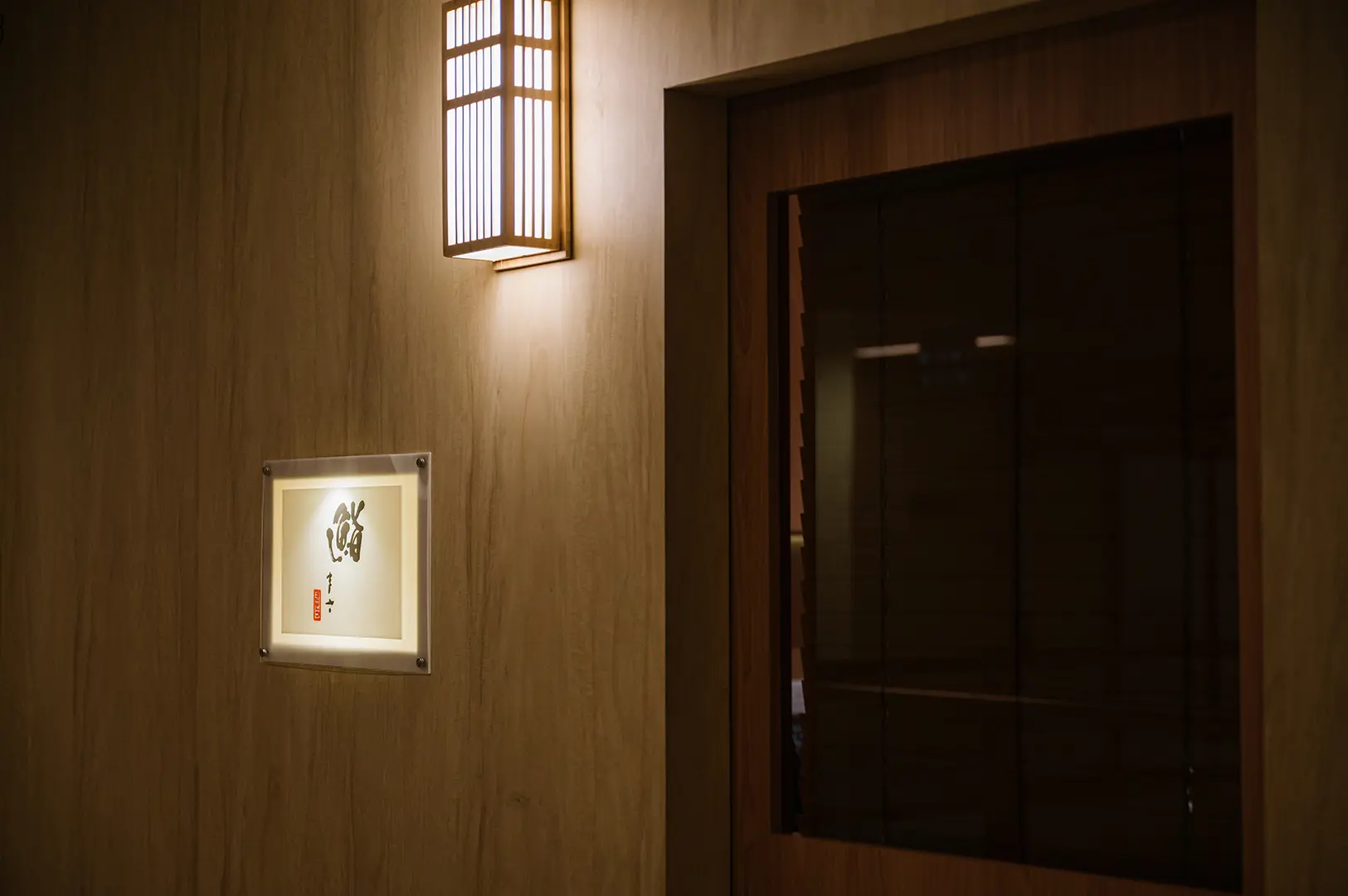Sushi Sama entrance with warm wood interiors, Japanese-style lighting, and a traditional doorway creating an intimate dining atmosphere.