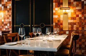 Elegant restaurant dining table set with wine glasses, white linens, and warm ambient lighting against decorative tiled walls, perfect for romantic date nights in Singapore