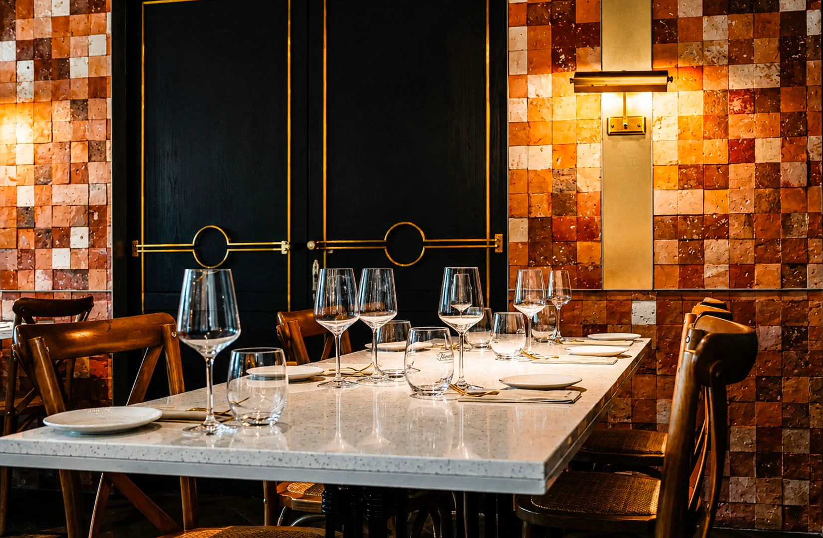 Elegant restaurant dining table set with wine glasses, white linens, and warm ambient lighting against decorative tiled walls, perfect for romantic date nights in Singapore