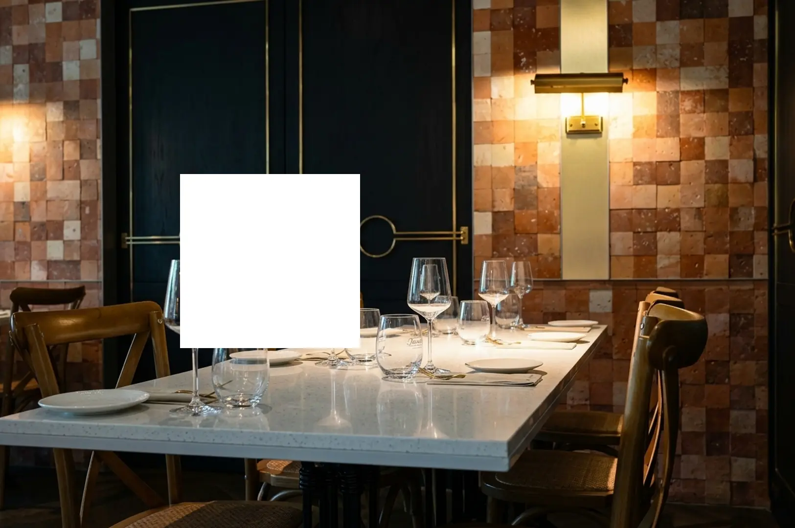 Elegant restaurant dining table set with wine glasses, white linens, and warm ambient lighting against decorative tiled walls, perfect for romantic date nights in Singapore