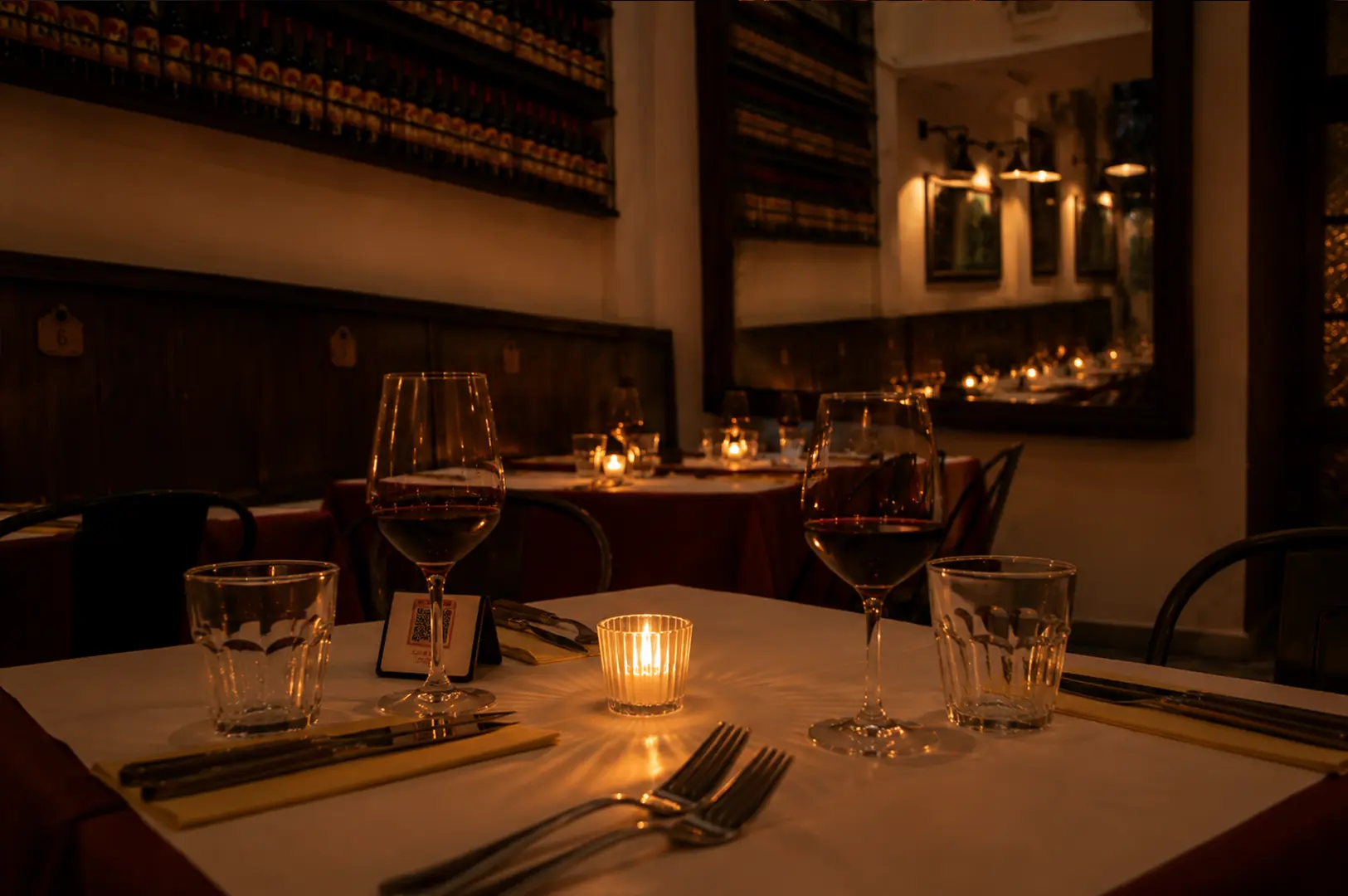 Elegant candlelit restaurant table with wine glasses in a warm and intimate dining setting.