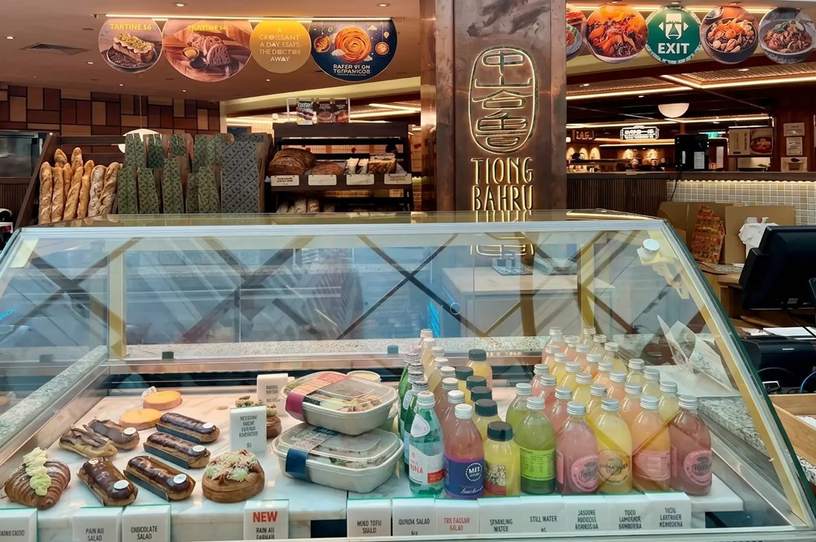 Tiong Bahru bakery counter displaying fresh pastries, breads, bottled beverages, and salads in a refrigerated glass display case