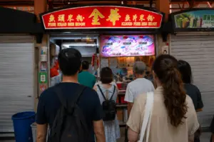 Customers wait in a long queue at the Kim Hua Fish Head Bee Hoon stall in a local hawker center