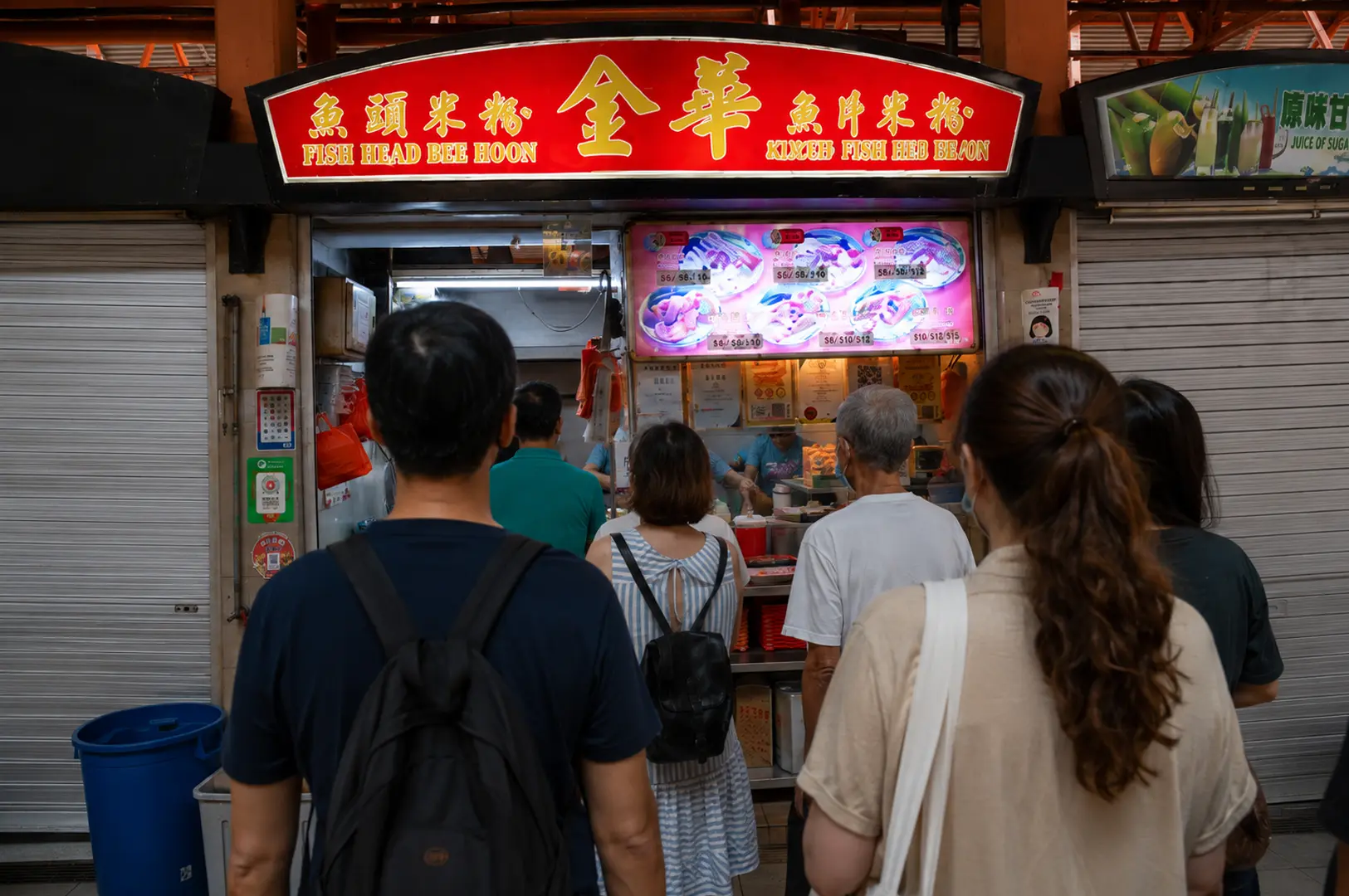 Customers wait in a long queue at the Kim Hua Fish Head Bee Hoon stall in a local hawker center