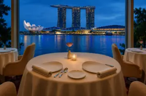 Elegant round dining table set for two with a stunning night view of Marina Bay Sands and the ArtScience Museum