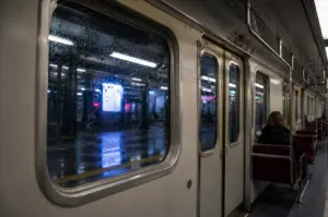 Train interior with rain-covered windows and lone passenger