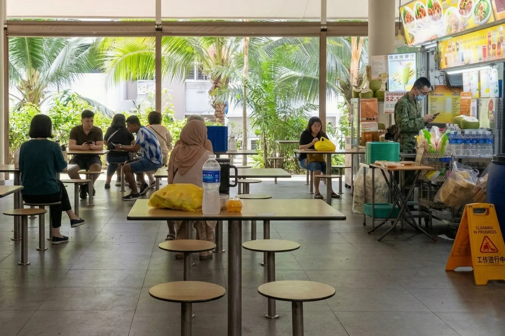 Open-air hawker center with diners and palm trees