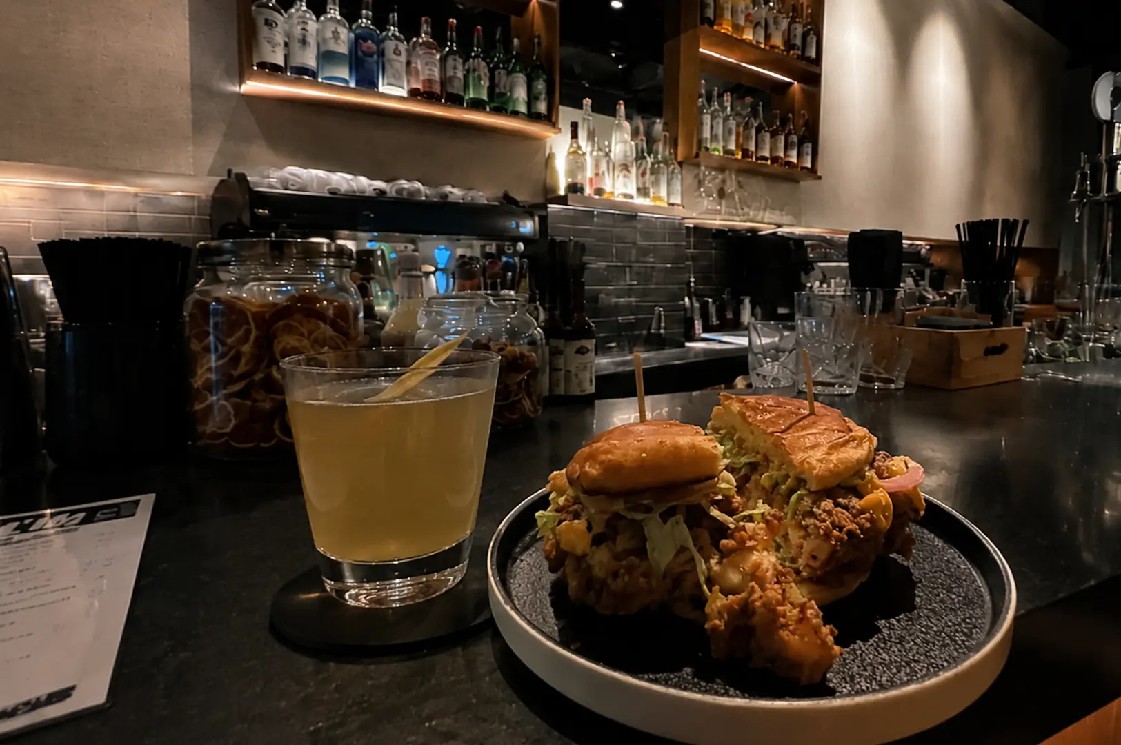 Gourmet sliders paired with a handcrafted cocktail at a hidden Singapore bar, highlighting the venue's food and drink offerings