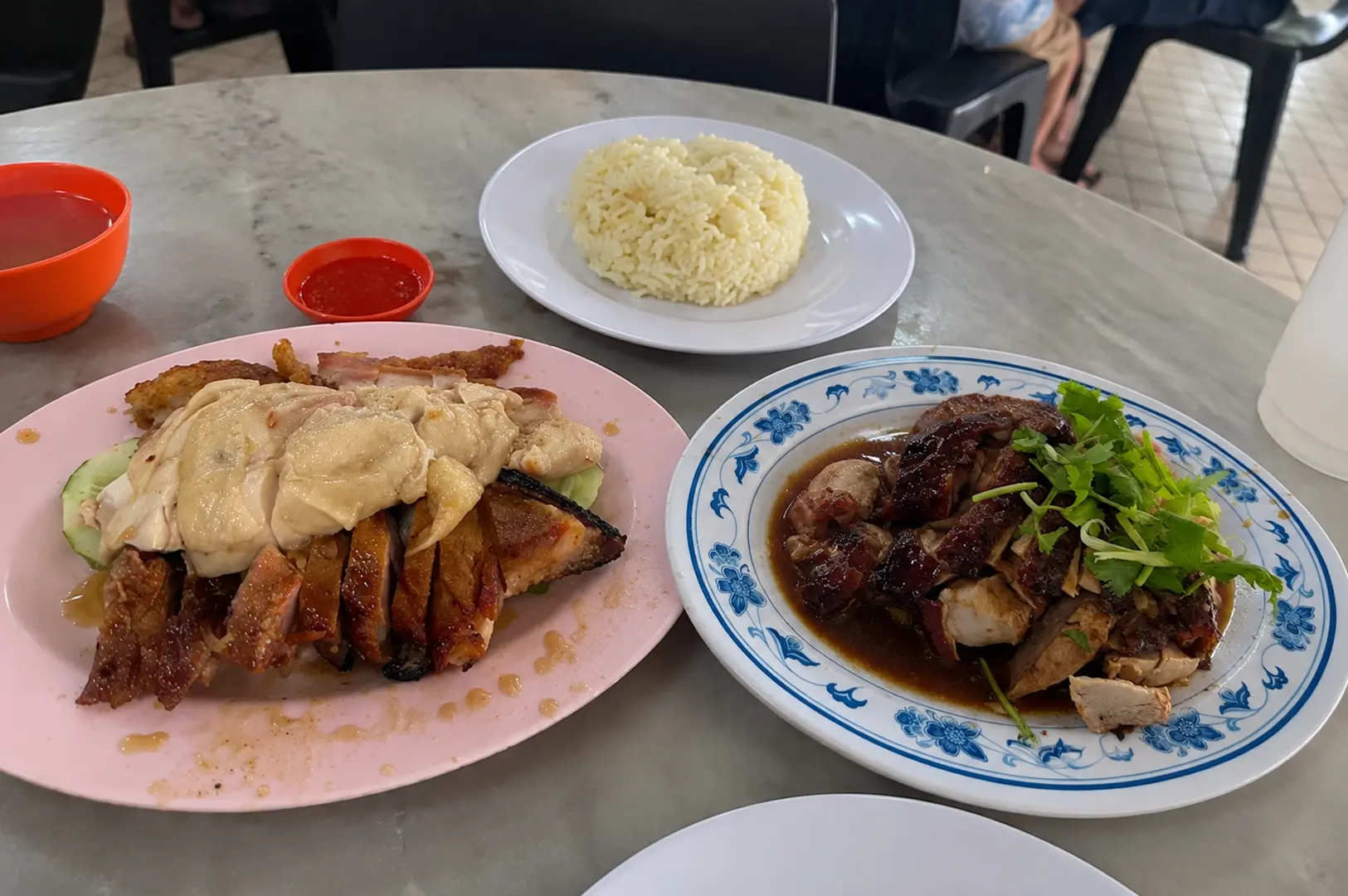 Mixed roasted and poached chicken plates with rice and chili sauce on marble table