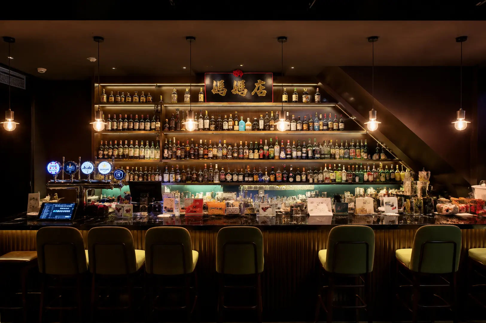 Wide view of a Singapore bar showcasing an extensive back bar lined with premium spirits and a curated collection of bottles