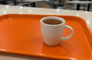 A cup of traditional kopi served on an orange tray at a Singapore food court.