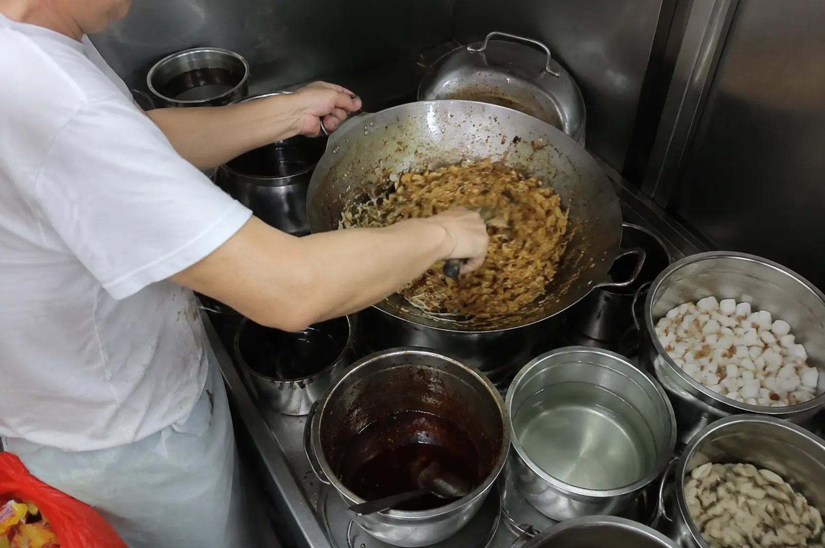 Hawker uncle cooking char kway teow in a wok at a Singapore food stall