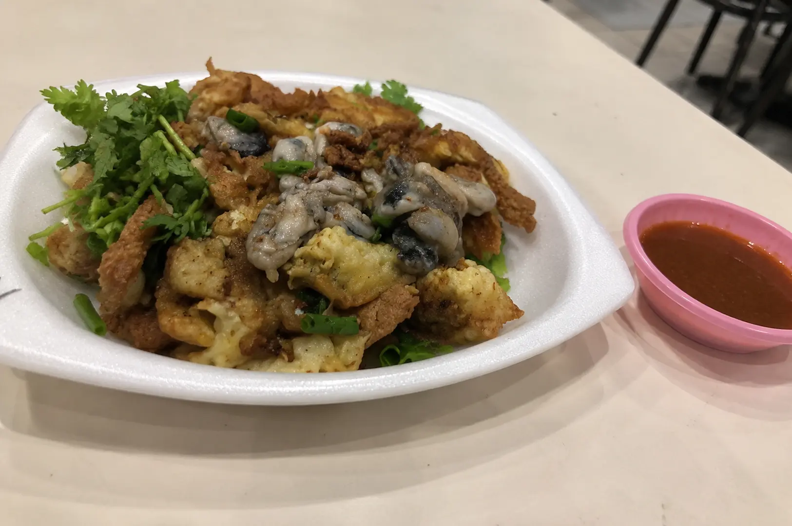 Crispy fried oyster omelette topped with fresh plump oysters and cilantro, served with a side of chili sauce