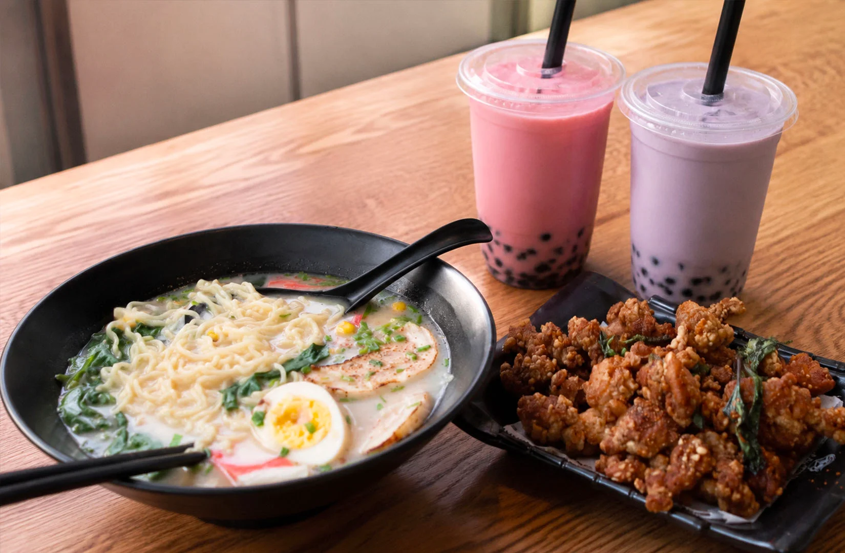 A table featuring ramen, fried chicken, and bubble tea, representing popular Asian food trends that have become familiar in Singapore’s dining scene.