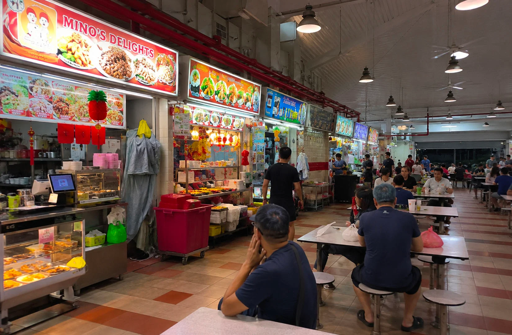 Tanjong Pagar hawker centre interior with food stalls, diners, and shared seating areas.