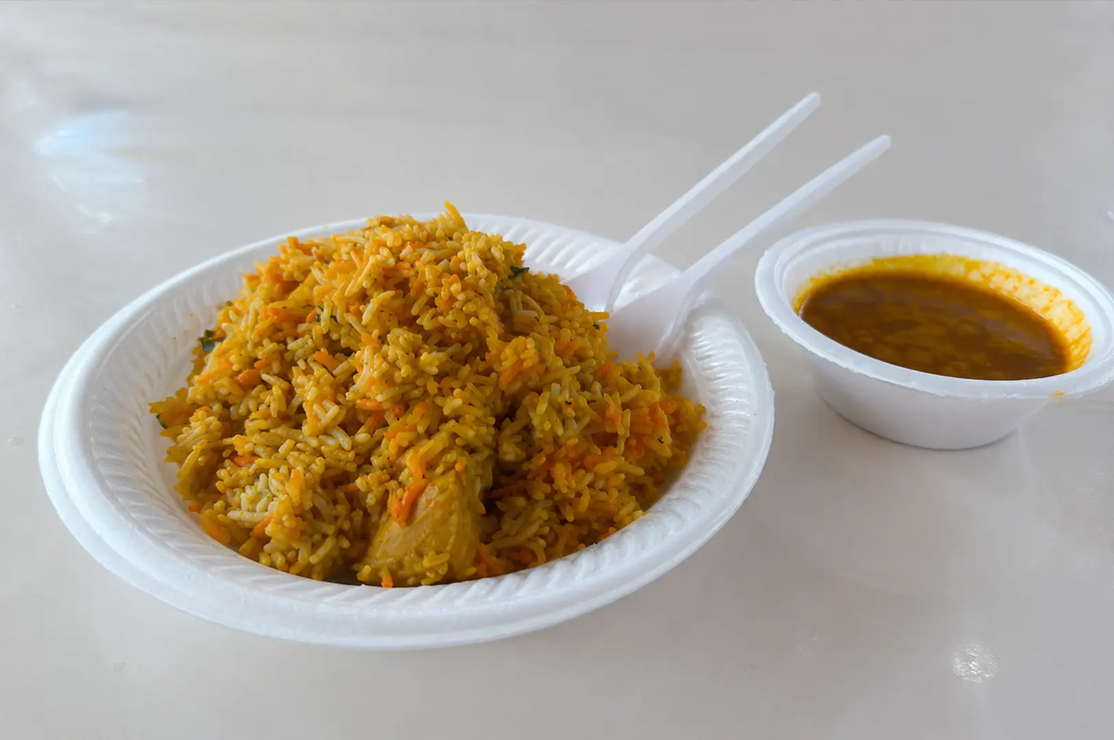 Plate of fragrant chicken biryani served with a bowl of rich curry gravy.