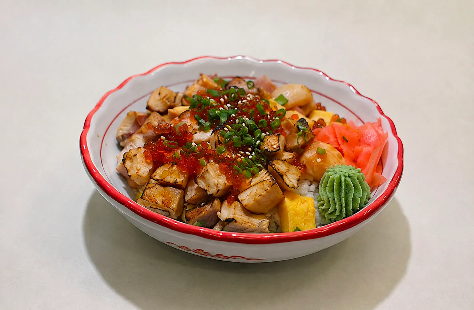 Fatty tuna, sea urchin, and salmon roe rice bowl with shiso leaf.