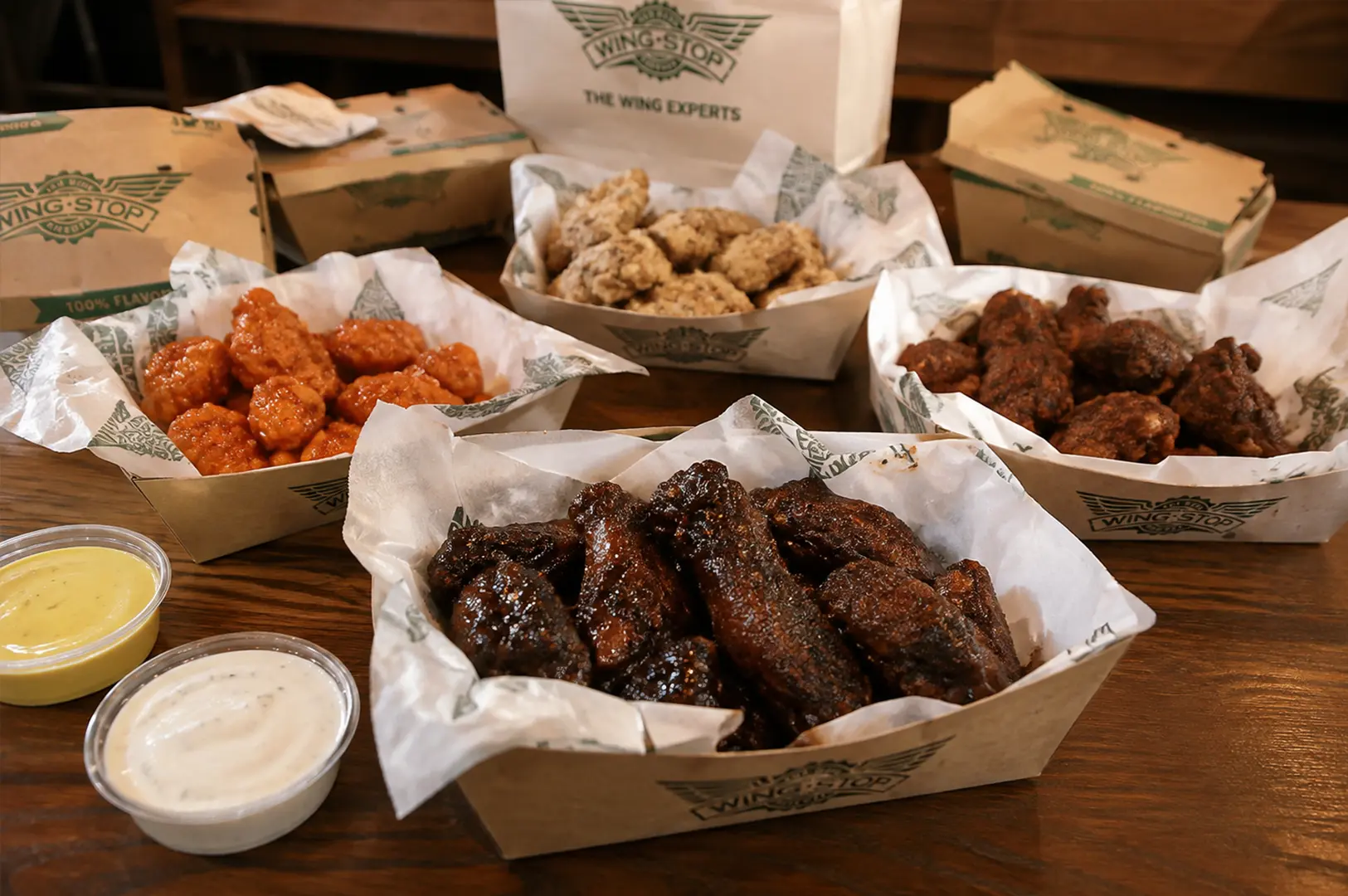 Variety of Wingstop chicken wings with multiple flavors, dipping sauces, and takeaway boxes.