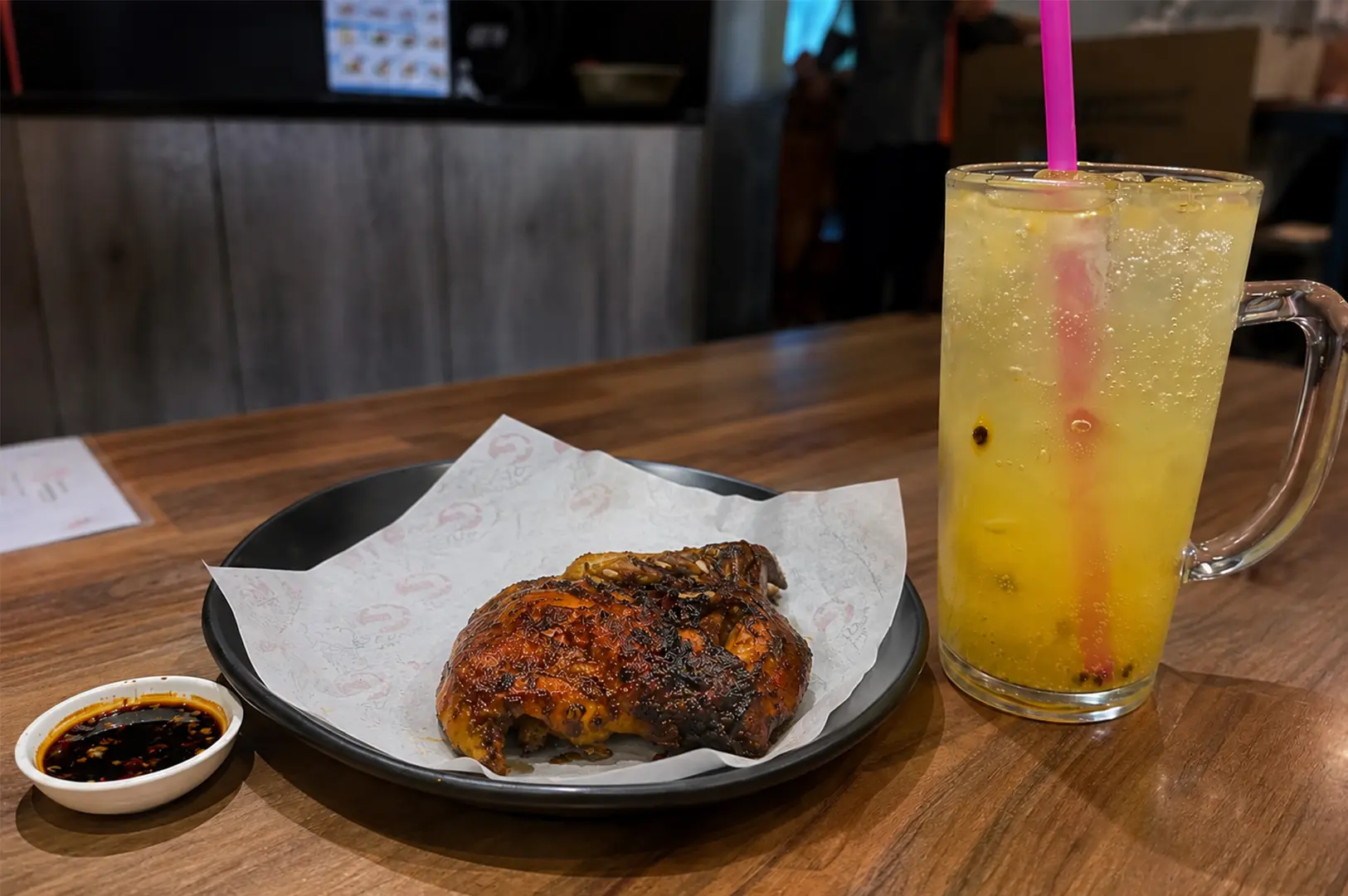 Grilled Ayam Penyet President chicken served with a dipping sauce and a refreshing passion fruit soda.