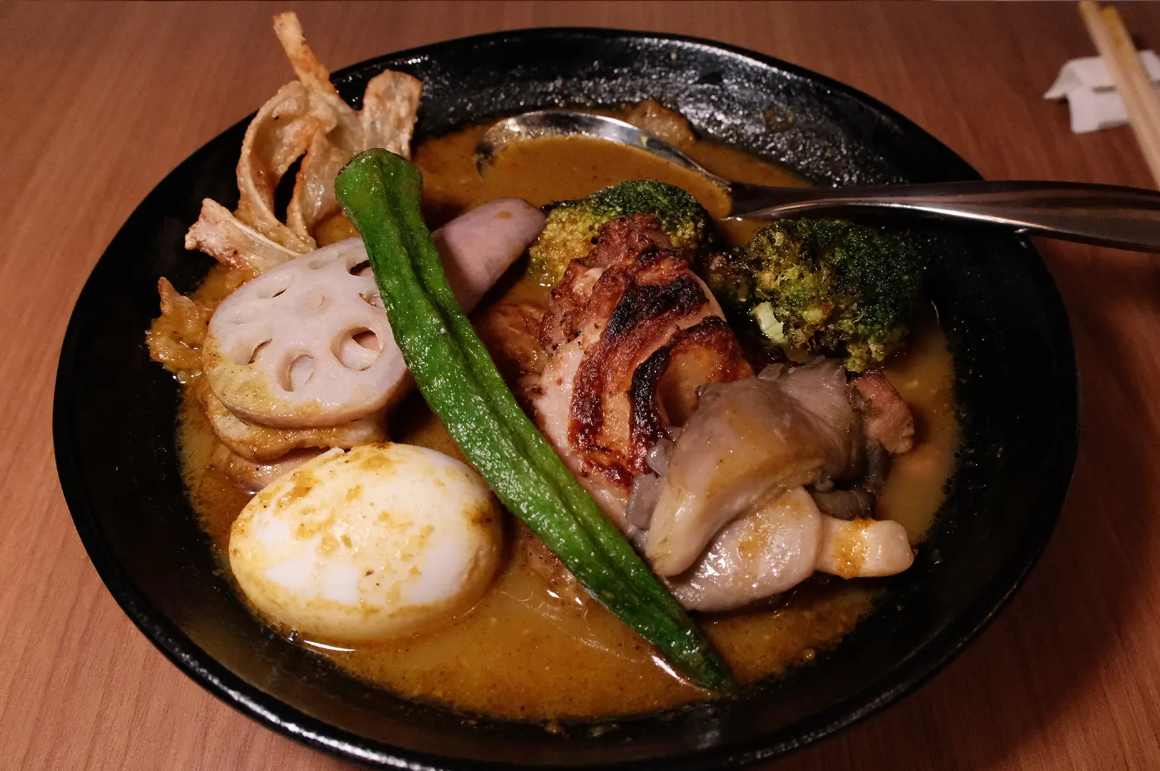 Close-up of Hokkaido soup curry by Ki-setsu Singapore with grilled chicken, vegetables, and a soft-boiled egg.