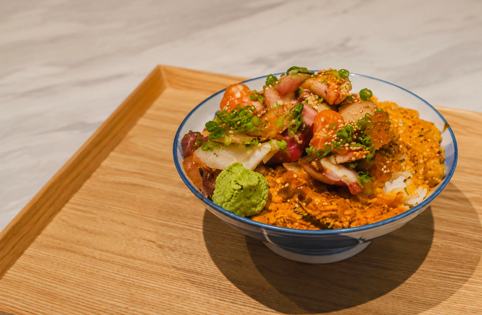 Mixed seafood rice bowl topped with creamy spicy sauce and fresh seafood.