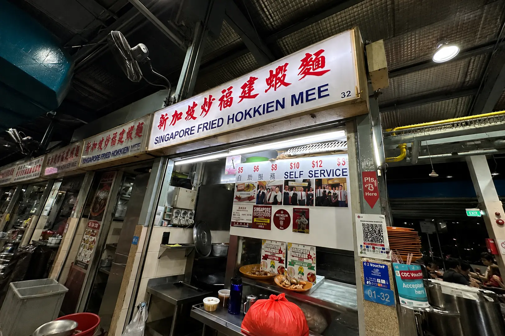 Singapore Fried Hokkien Mee hawker stall with illuminated signboard and self-service counter at a Singapore food centre.