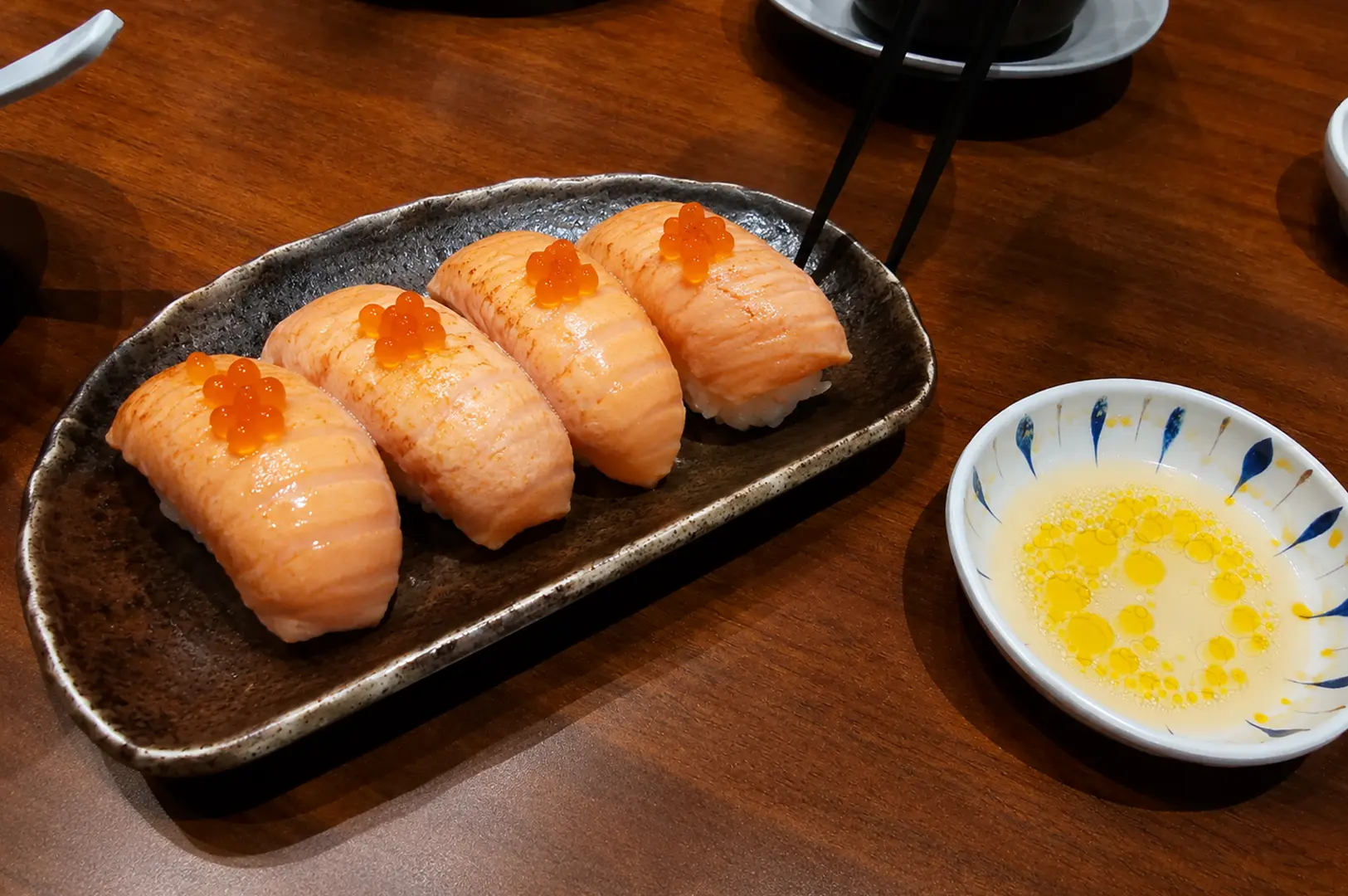 Seared salmon nigiri topped with salmon roe, served with a buttery dipping sauce.