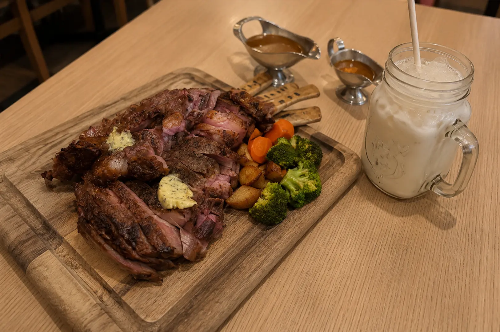 The MeatHouse grilled mixed meat platter served with vegetables, sauces, and a chilled drink.