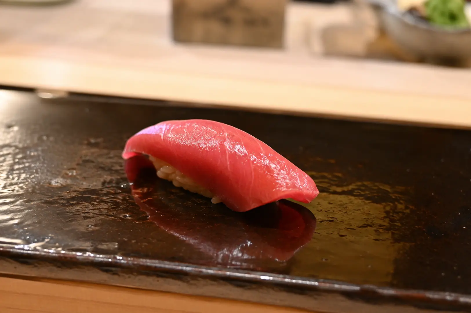 Premium fatty tuna nigiri served on a ceramic plate at a sushi counter.
