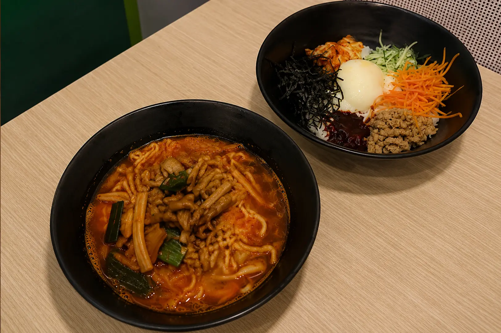 Jinjja Kitchen Korean spicy ramen with bibimbap topped with vegetables and a soft-boiled egg.