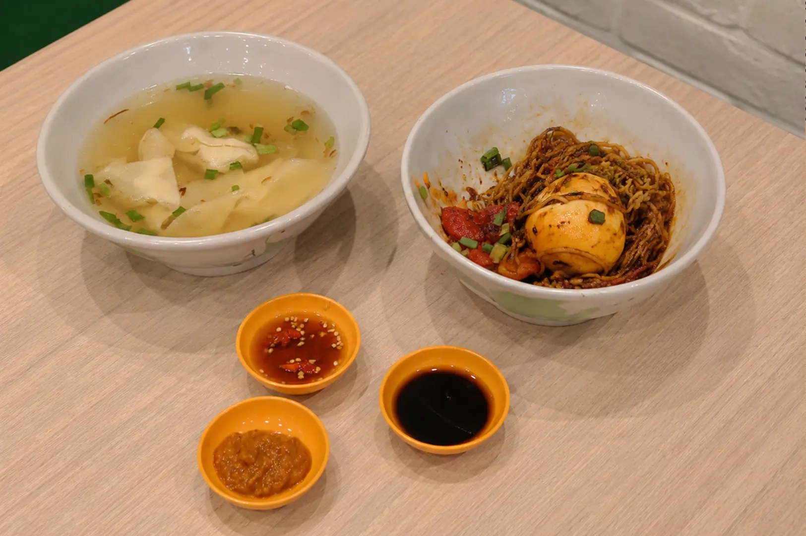 Tan dry noodles with braised egg, wonton soup, and three dipping sauces.